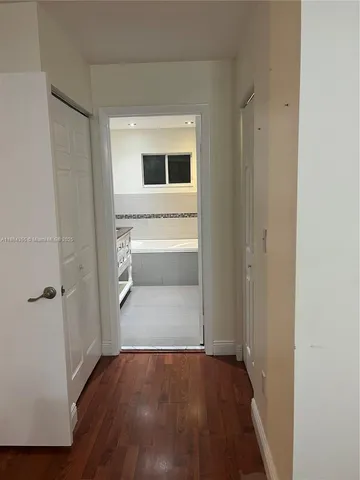 a view of a hallway with wooden floor and closet