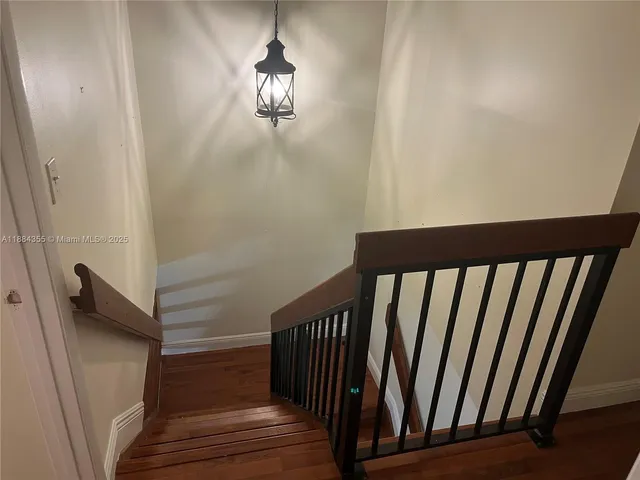 a view of staircase with railing and a chandelier
