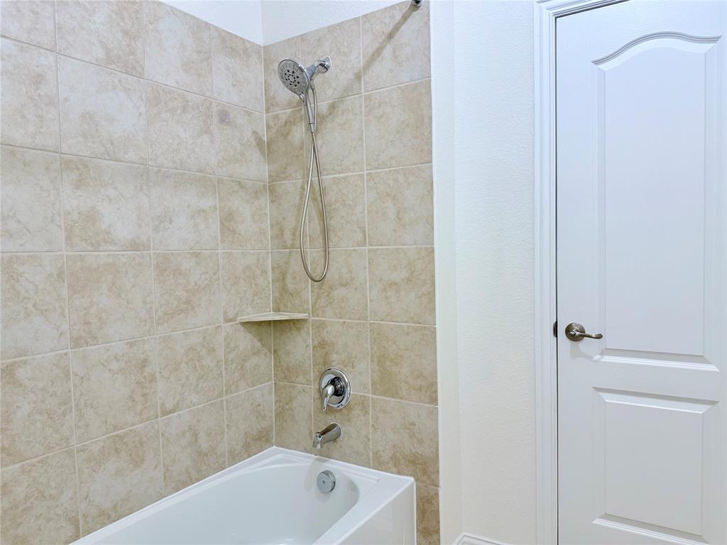 1336 Morning View Road Georgetown, TX 78628 - Photo 33 of 40 A well-appointed bathroom features a tub and shower combination with stylish tile surround and a convenient corner shelf.