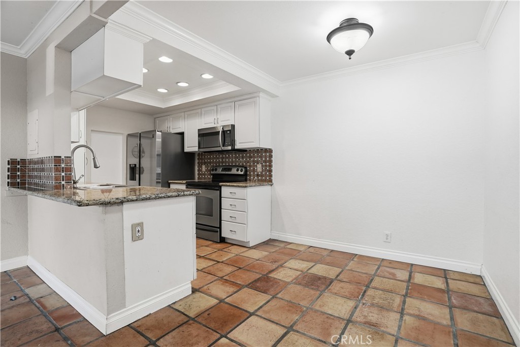 20702 El Toro Road, Unit 231 Lake Forest, CA 92630 - Photo 18 of 36 a kitchen with kitchen island granite countertop a sink cabinets and stainless steel appliances