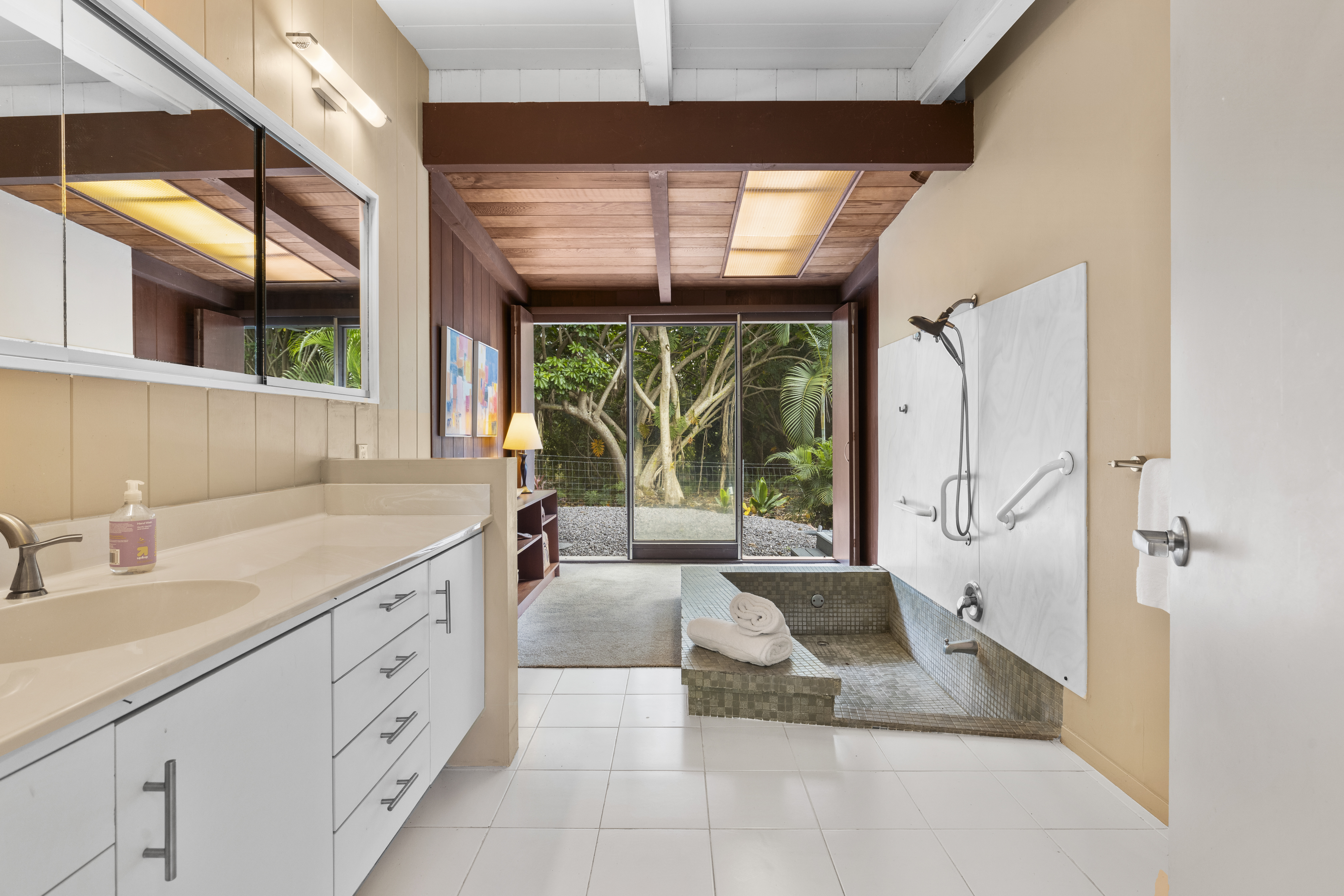 83-5369 Manako Road Captain Cook, HI 96704 - Photo 20 of 30 a spacious bathroom with a double vanity sink a large mirror and a bathtub next to a window
