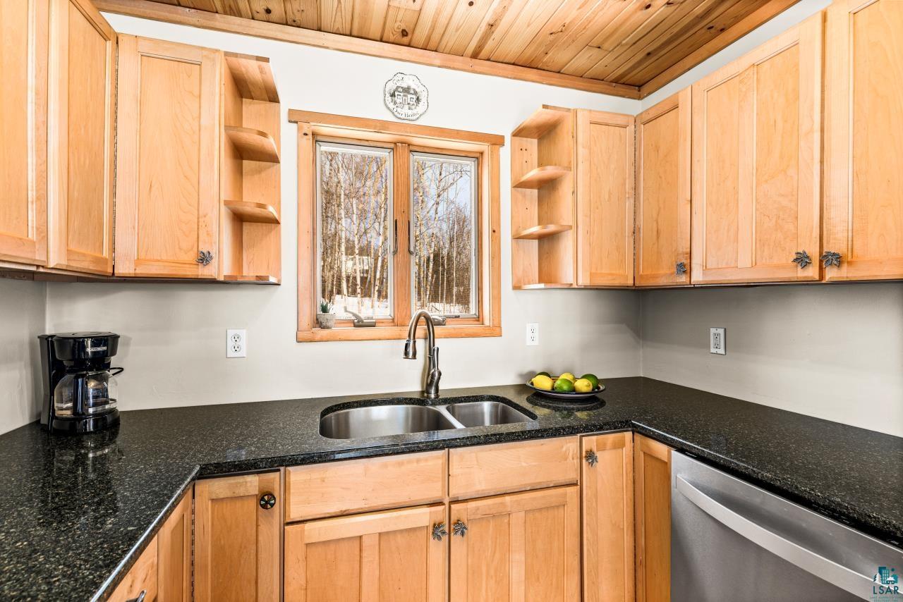 67 Snowshoe Trail Tofte, MN 55615 - Photo 24 of 42 Kitchen featuring dishwasher, open shelves, dark stone counters, and light wood finish cabinets