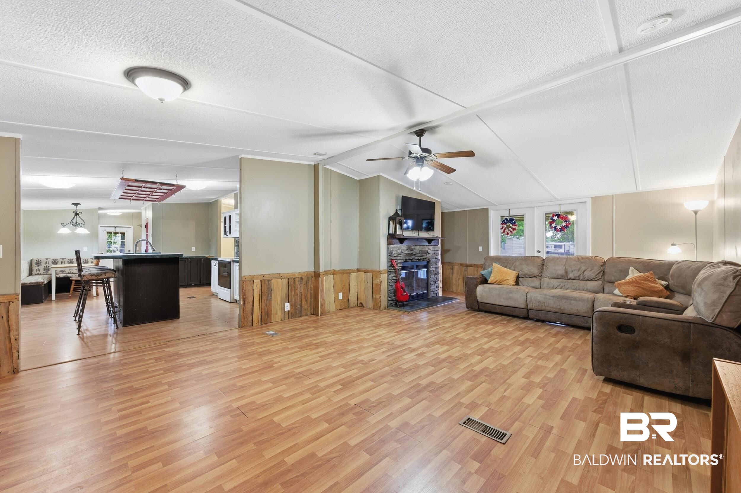 926 Tumbling Lane Atmore, AL 36502 - Photo 15 of 56 Spacious living area featuring wood-finish flooring, a stone fireplace, and a ceiling fan