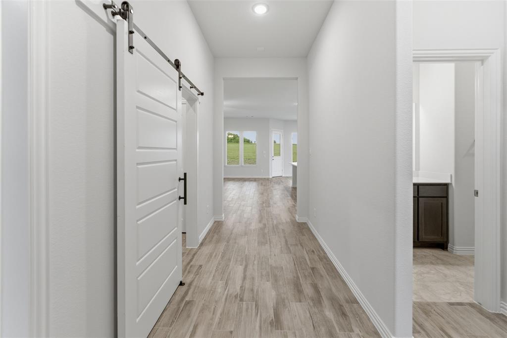 119 Hillview Trail Decatur, TX 76234 - Photo 12 of 30 Hallway featuring wood-finish flooring, recessed lighting, and a white barn door with black hardware