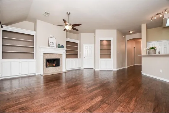 a view of a livingroom with a fireplace a ceiling fan and wooden floor