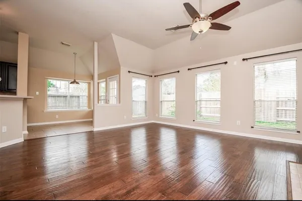 a view of an empty room with wooden floor and a window