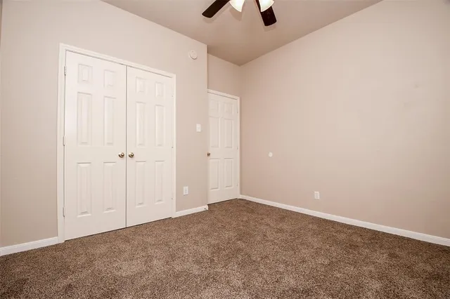 an empty room with closet and a chandelier fan