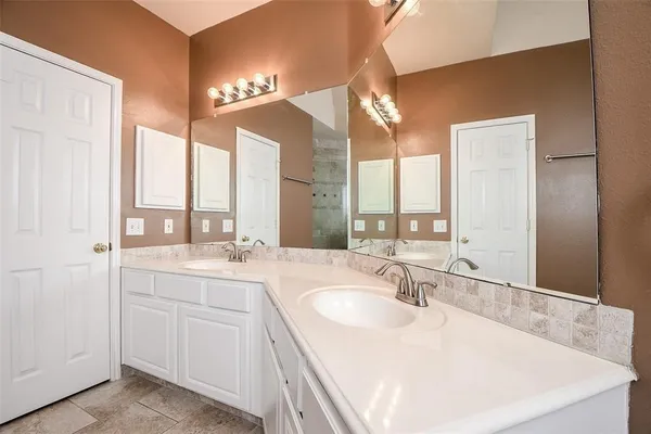 a bathroom with double vanity and a mirror