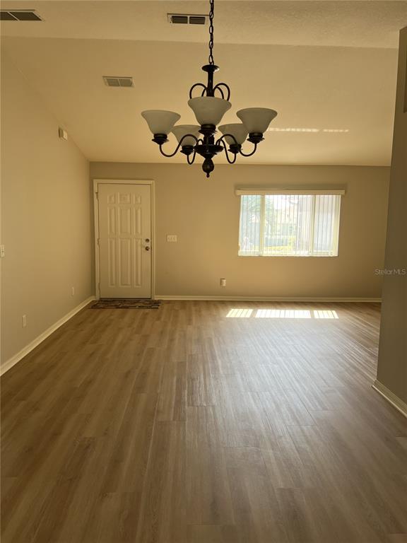 6035 Southwest 98th Street Road Ocala, FL 34476 - Photo 2 of 15 a view of a room with wooden floor and chandelier