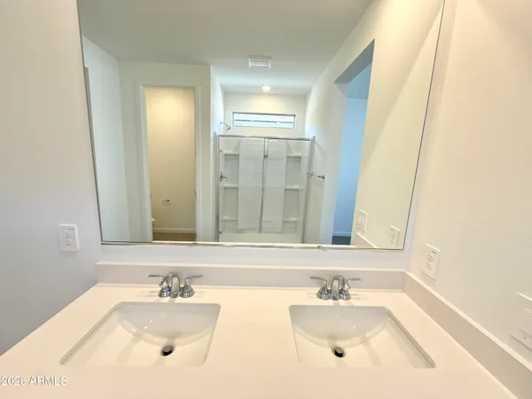 a spacious bathroom with a double vanity sink a mirror and a shower