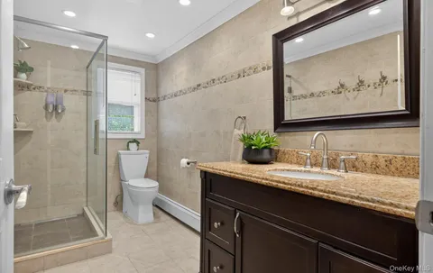 a bathroom with a granite countertop sink a toilet and shower