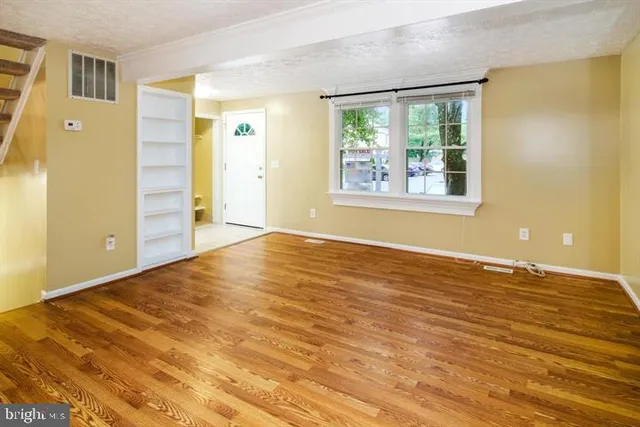a view of an empty room with a window and a kitchen