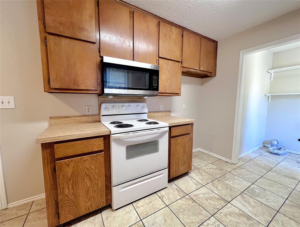 1106 Curtis Drive, Unit A Weatherford, TX 76086 - Photo 7 of 13 a kitchen with stainless steel appliances granite countertop a sink stove and microwave