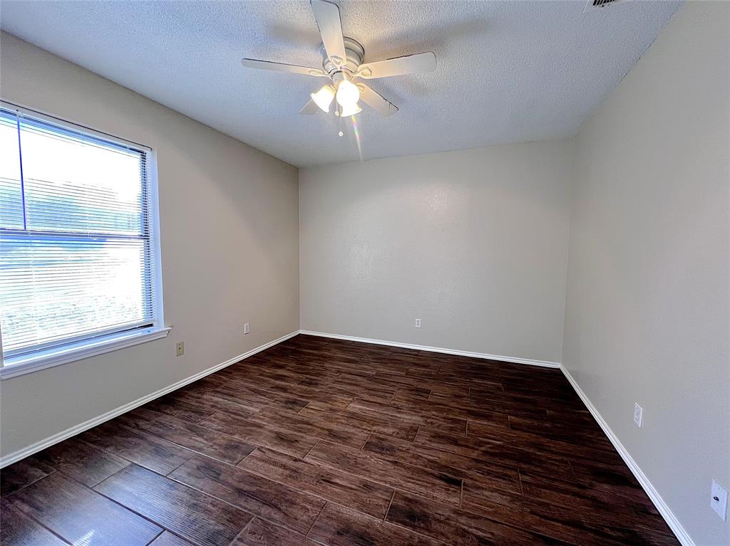1106 Curtis Drive, Unit A Weatherford, TX 76086 - Photo 10 of 13 an empty room with wooden floor fan and windows