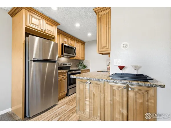 a kitchen with stainless steel appliances granite countertop a refrigerator a stove and a sink with wooden floor