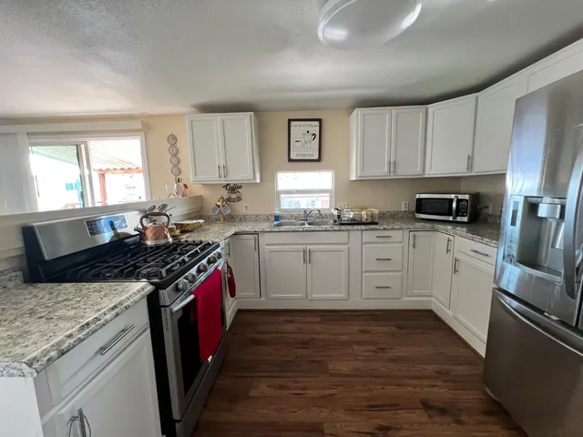 a kitchen with granite countertop wooden cabinets stainless steel appliances a sink and a window