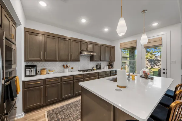 a kitchen with stainless steel appliances a sink a stove a refrigerator and cabinets