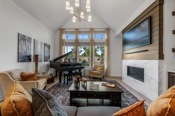 a living room with furniture a flat screen tv and a floor to ceiling window