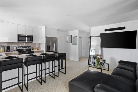 a living room with furniture a flat screen tv and kitchen view