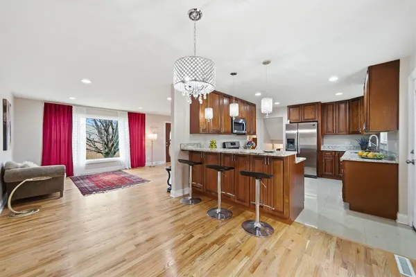a view of kitchen with stainless steel appliances granite countertop sink stove refrigerator and wooden floor
