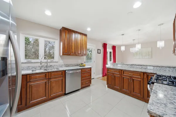 a large kitchen with stainless steel appliances granite countertop a sink and cabinets