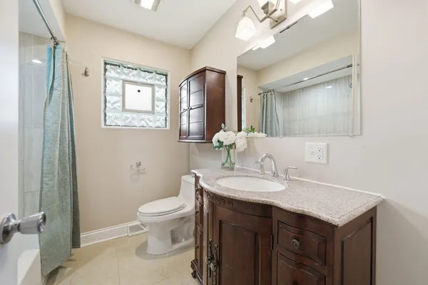 a bathroom with a granite countertop sink a toilet and a mirror
