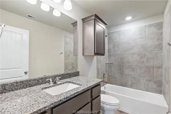 a bathroom with a granite countertop sink toilet and shower