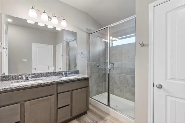 a bathroom with a granite countertop sink a mirror and a shower