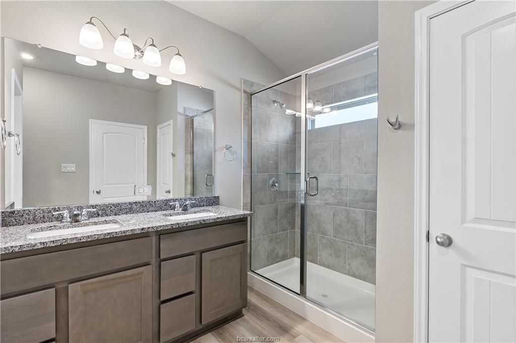 2119 Chief Street Bryan, TX 77807 - Photo 20 of 23 a bathroom with a granite countertop sink a mirror and a shower