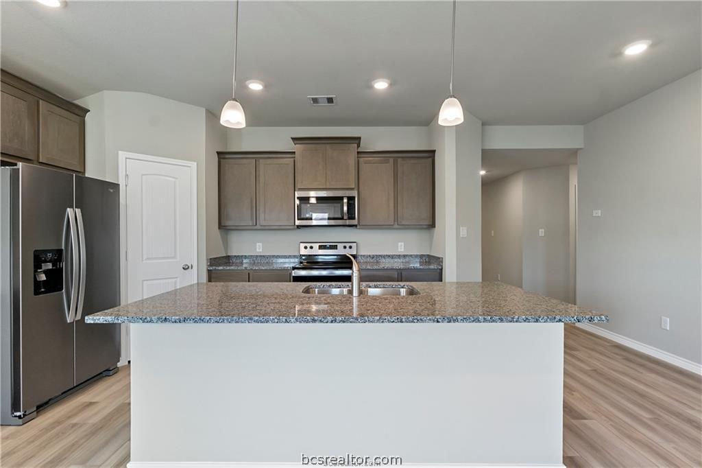 2119 Chief Street Bryan, TX 77807 - Photo 5 of 23 a kitchen with stainless steel appliances granite countertop a refrigerator a sink a stove a microwave and white cabinets with wooden floor