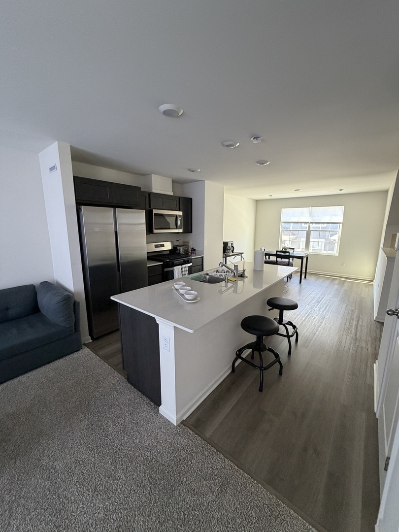 1555 Sequoia Way Pingree Grove, IL 60140 - Photo 3 of 17 a living room with couches and kitchen view with wooden floor