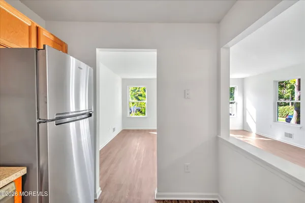 a view of an empty room with window and wooden floor