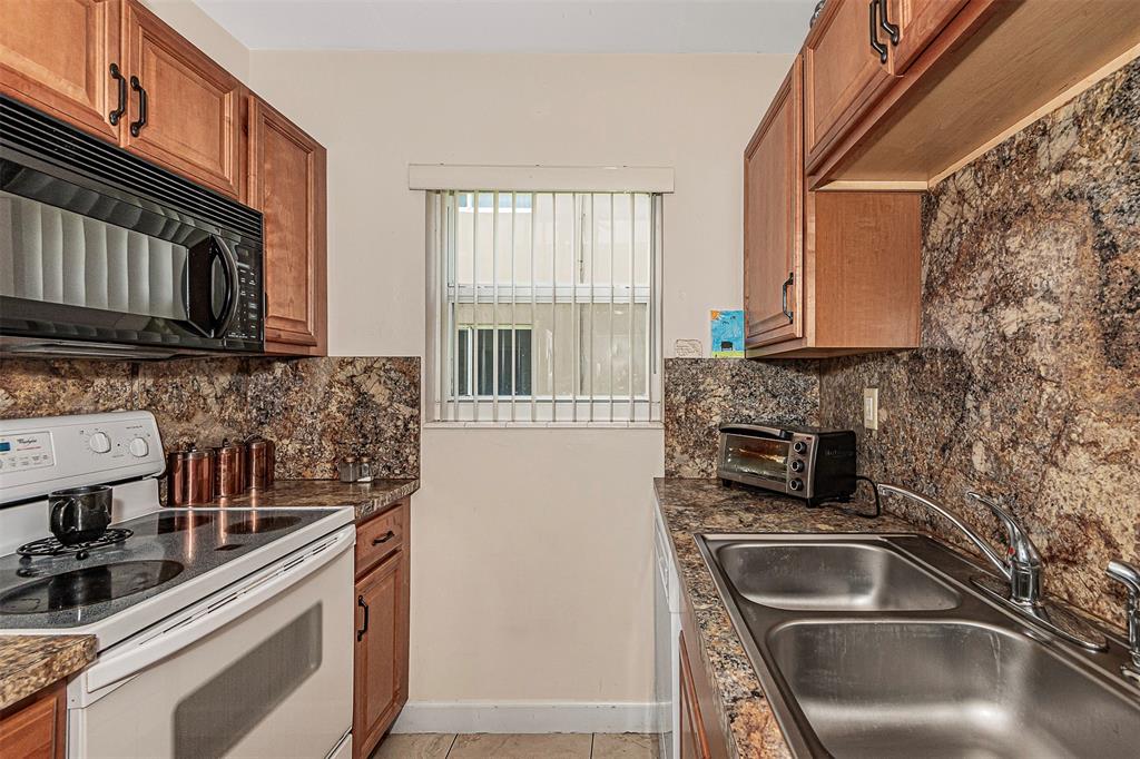 2131 Northeast 40th Court, Unit 18 Lighthouse Point, FL 33064 - Photo 18 of 36 a kitchen with granite countertop a sink and a stove top oven