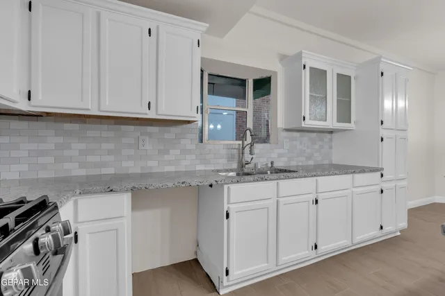 a kitchen with stainless steel appliances granite countertop white cabinets a sink a stove a microwave and view living room