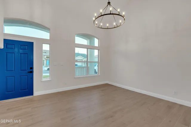 en empty room with windows and chandelier