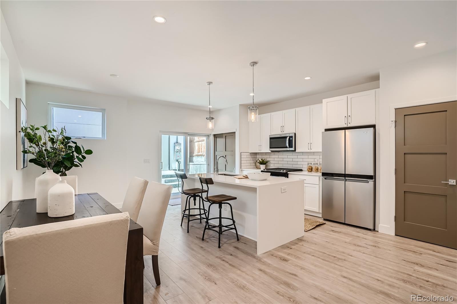 1255 Perry Street Denver, CO 80204 - Photo 4 of 28 a kitchen with a refrigerator a stove top oven a sink dishwasher with a dining table and chairs