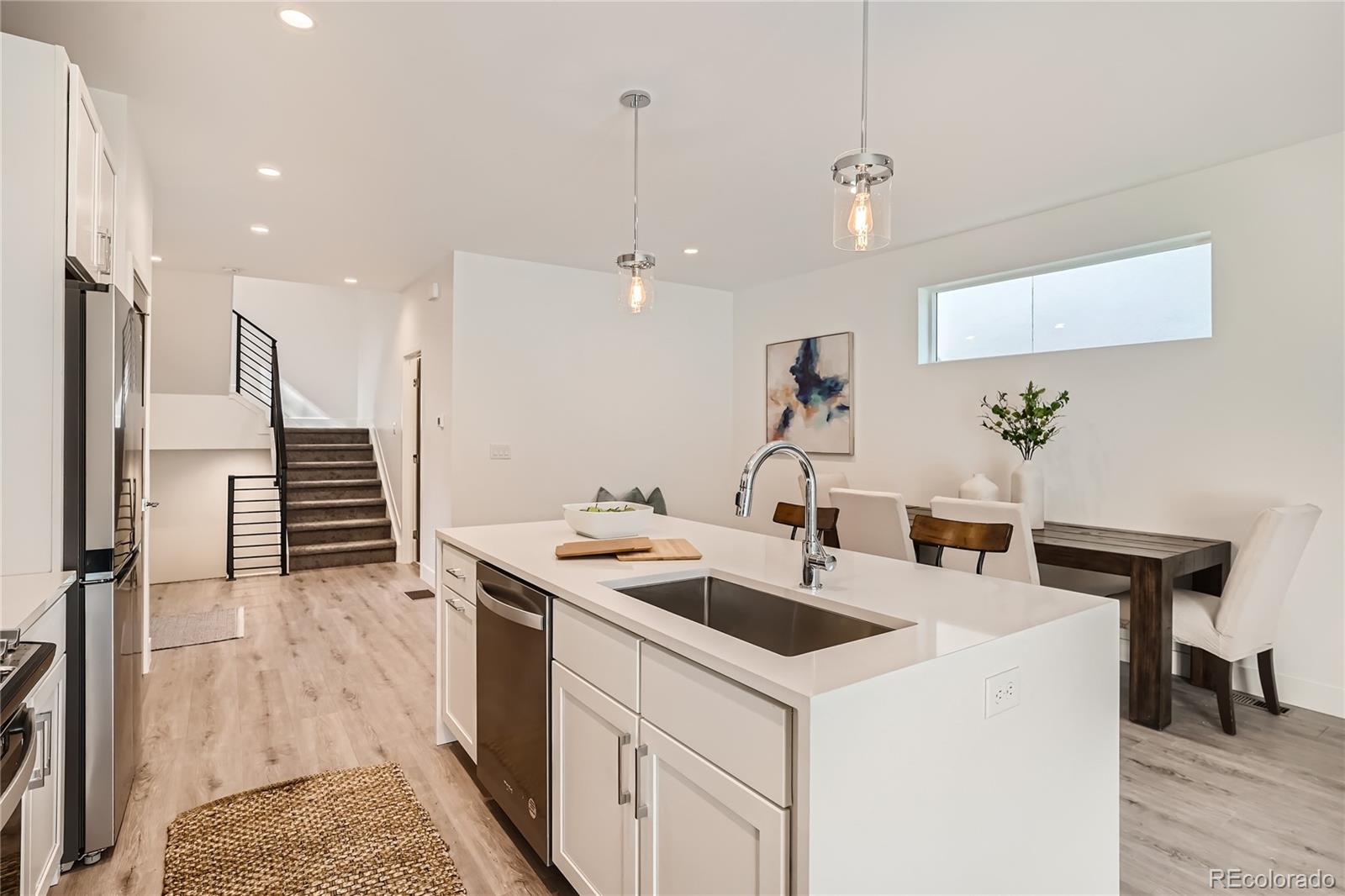 1255 Perry Street Denver, CO 80204 - Photo 7 of 28 a kitchen that has a sink a microwave oven a stove and white cabinets with wooden floor