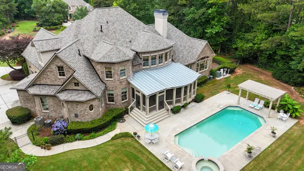 an aerial view of a house with swimming pool and outdoor seating