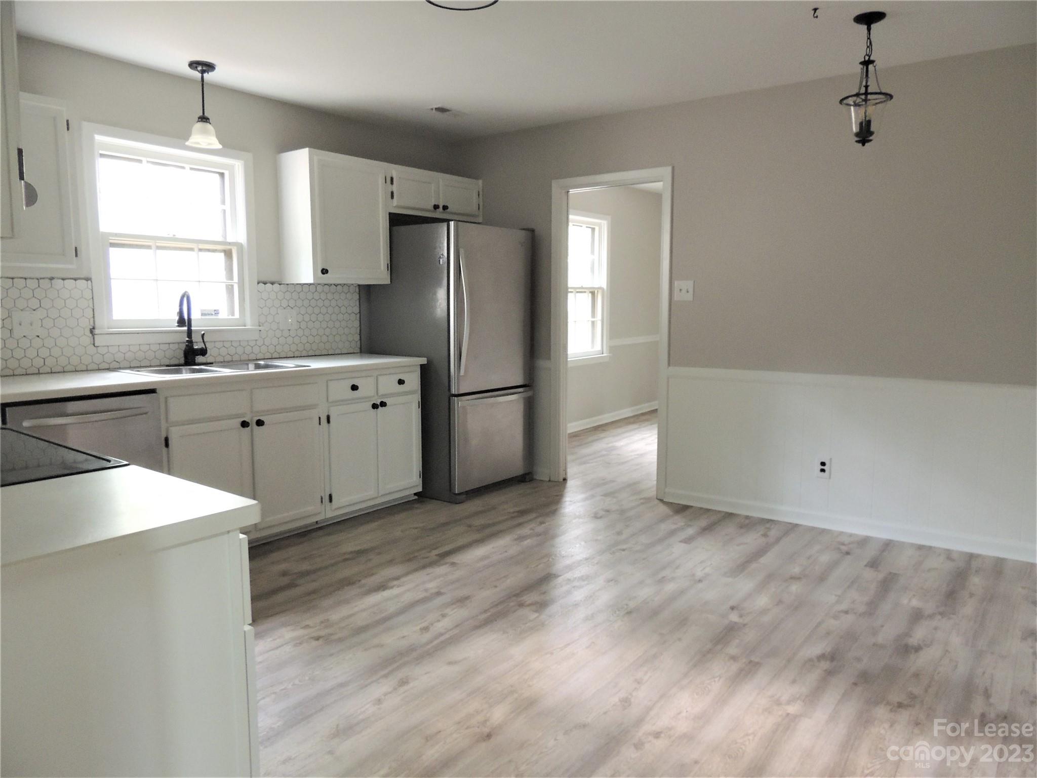 8700 Houston Ridge Road Charlotte, NC 28277 - Photo 7 of 29 a large kitchen with a refrigerator a sink dishwasher a stove and white cabinets with wooden floor
