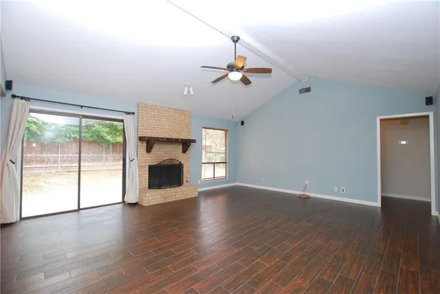 a view of empty room with wooden floor and fireplace