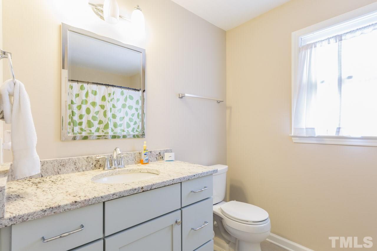6108 Ivy Ridge Road Raleigh, NC 27612 - Photo 15 of 23 a bathroom with a granite countertop toilet sink and mirror