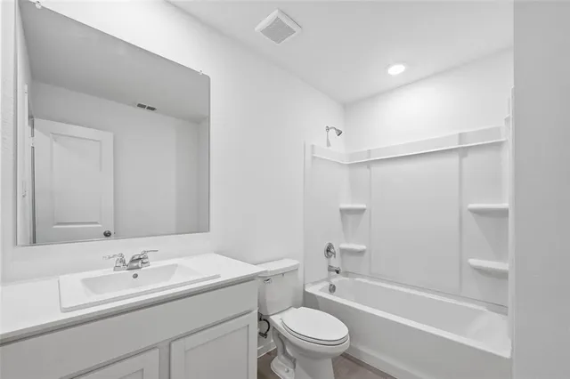 a bathroom with a bathtub shower sink vanity mirror and toilet