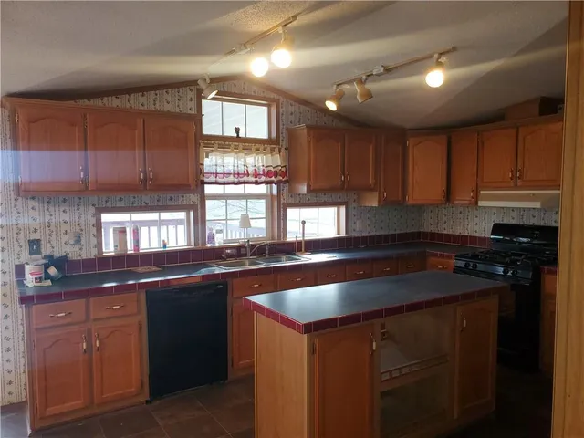 a kitchen with kitchen island granite countertop a sink stove and cabinets