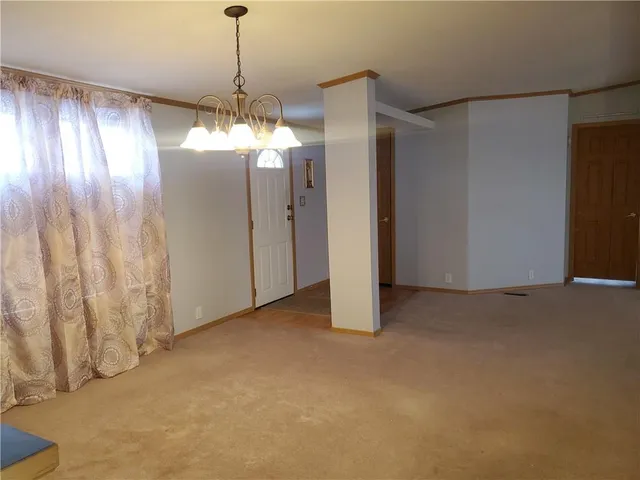 a view of an empty room with window and chandelier fan