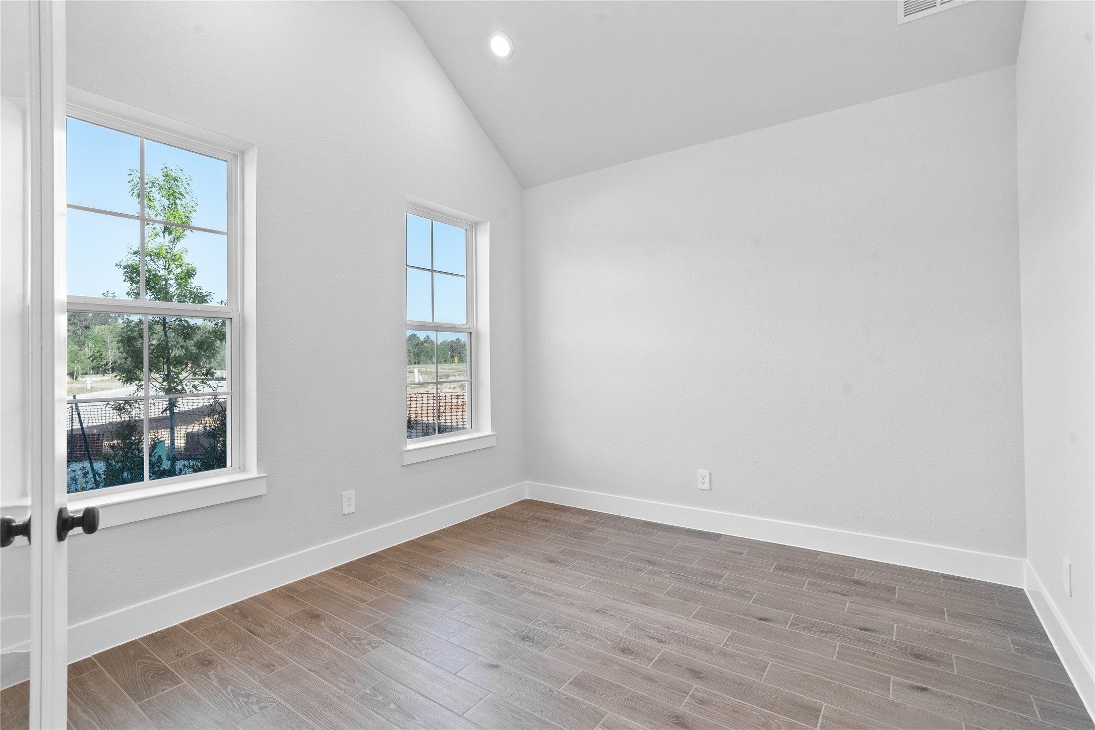 2114 Rowl Street Montgomery, TX 77316 - Photo 8 of 50 Tucked peacefully in the front of the home is the Study! The room features a stunning vaulted ceiling, large windows, wide-plank wood-look flooring, crisp walls w/oversized baseboards, and French doors. Whether used as a quiet home office, a library, or a cozy den, this space offers the perfect blend of functionality and high-end design.