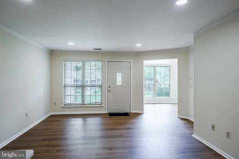 an empty room with wooden floor and windows with curtains