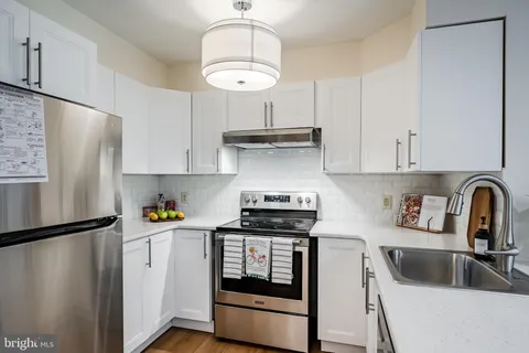 a kitchen with stainless steel appliances granite countertop a refrigerator a sink dishwasher a stove and white cabinets