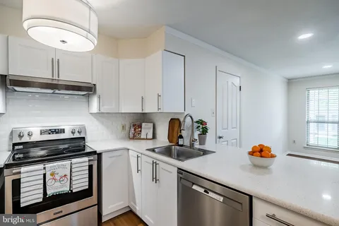 a kitchen with stainless steel appliances a sink a stove and white cabinets