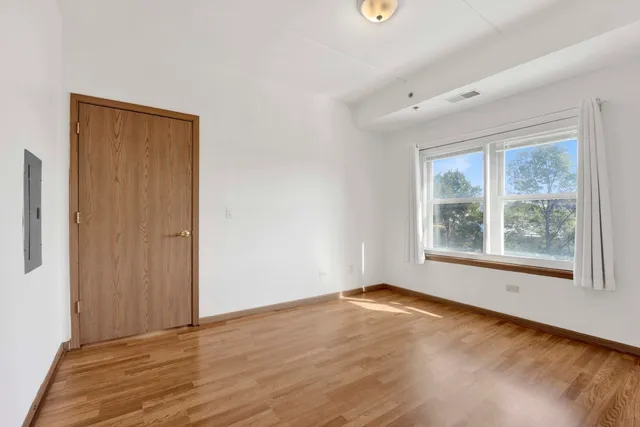 an empty room with wooden floor and windows