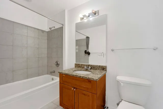 a bathroom with a granite countertop sink a toilet and shower